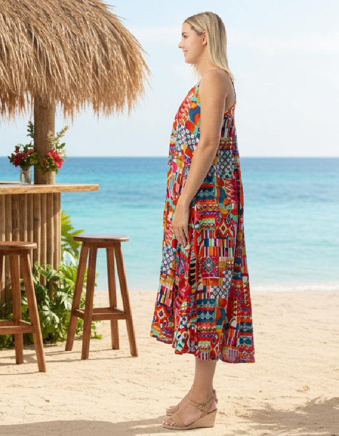 Woman in a colorful dress standing on a beach with ocean view
