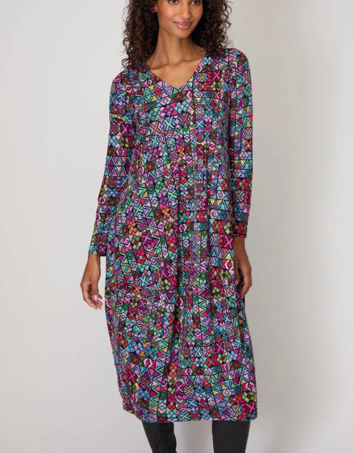 Woman wearing a colorful patterned dress against a plain background