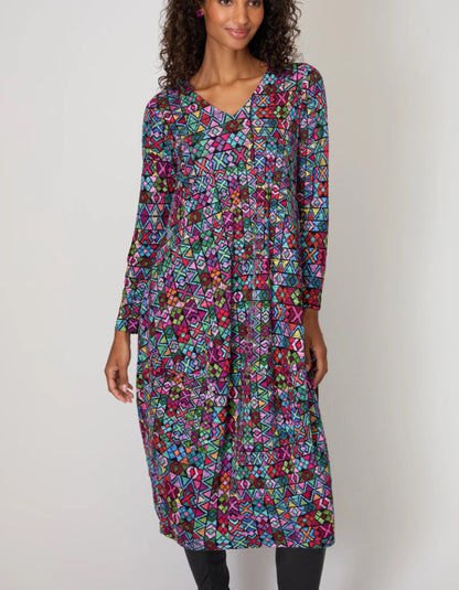Woman wearing a colorful patterned dress against a plain background