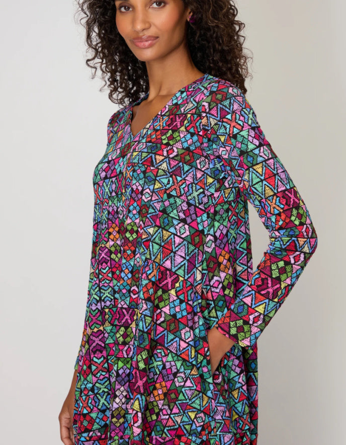 Woman wearing a colorful geometric patterned dress against a plain background