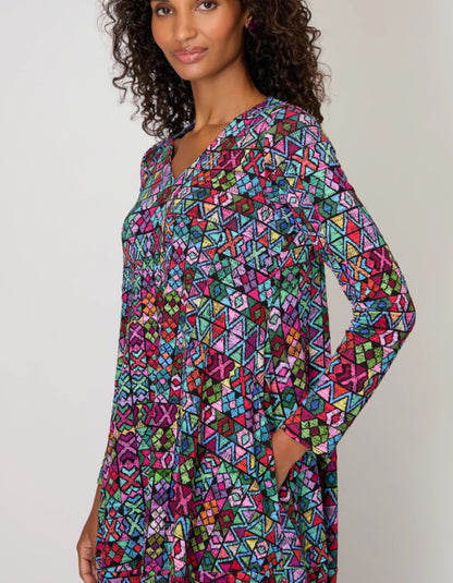 Woman wearing a colorful geometric patterned dress against a plain background
