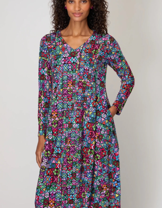 Woman wearing a colorful patterned dress against a plain background