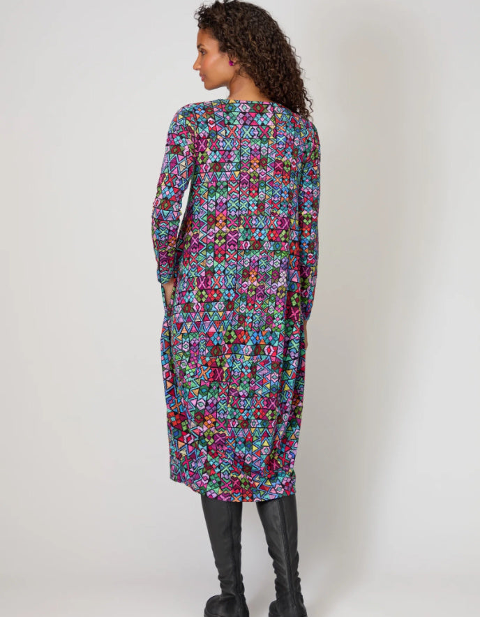 Woman wearing a colorful patterned dress against a white background