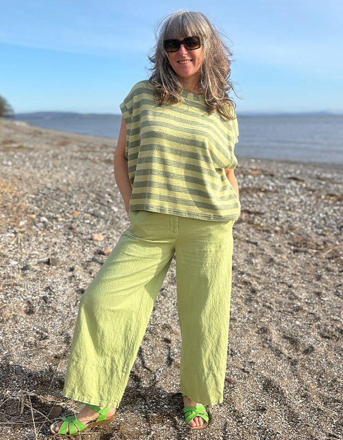 Woman in a green outfit standing on a beach with ocean in the background