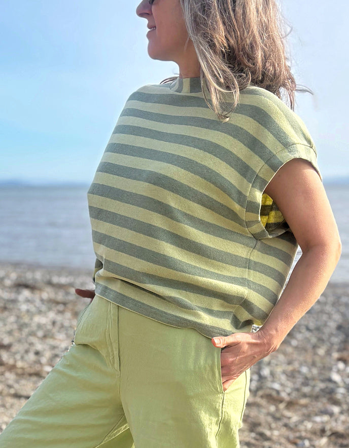 Person wearing a green and yellow striped shirt and pants on a beach.