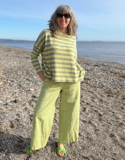 woman wearing stripe green and yellow boxy knit jumper with soft green wide leg trousers