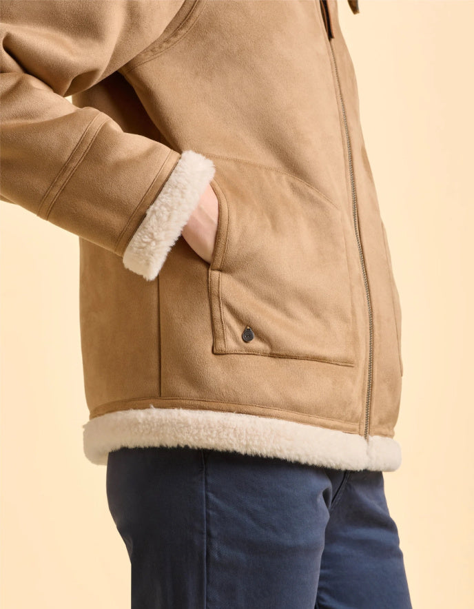 Close-up of a tan jacket with white fur lining on a beige background