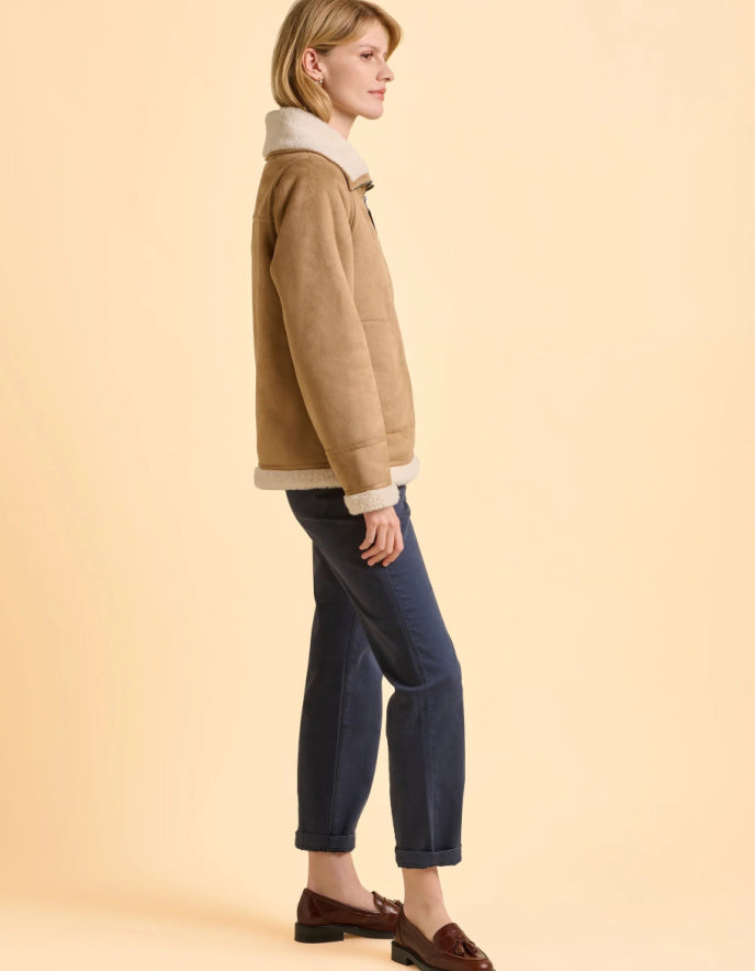 Woman wearing a brown jacket with white collar on a beige background