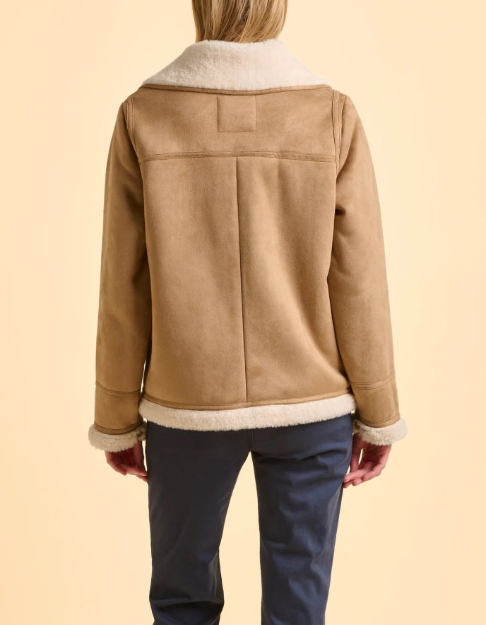 Person wearing a tan jacket with white lining on a beige background