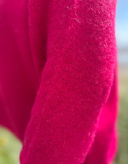 Close-up of a bright pink fabric texture with a blurred natural background