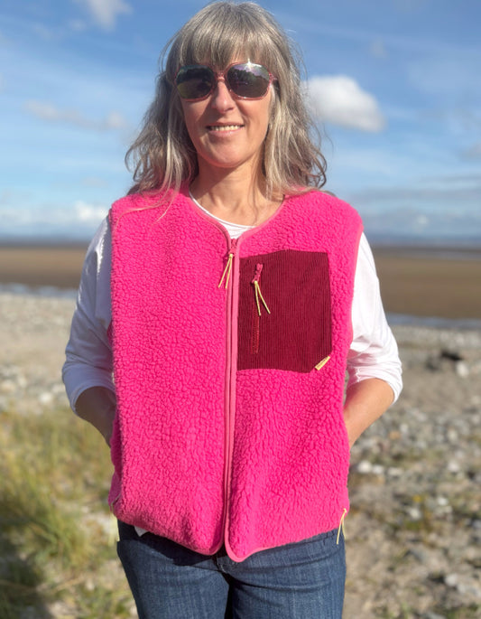 Person wearing a bright pink vest with a red pocket on a beach