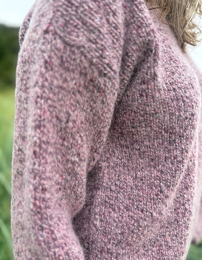 Close-up of a person wearing a textured pink sweater outdoors.