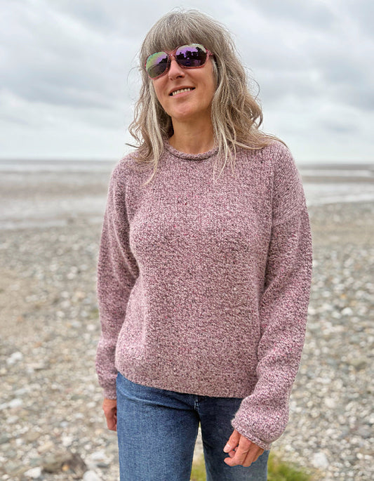 Woman wearing a pink sweater and sunglasses on a beach