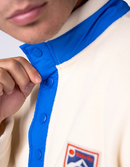 Close-up of a person wearing a jacket with a blue collar and a visible brand logo.