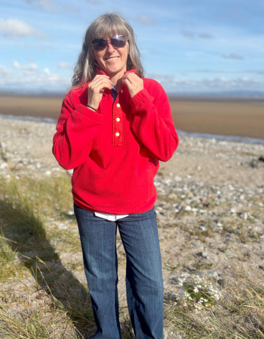 Person wearing a red sweater and sunglasses standing on a beach