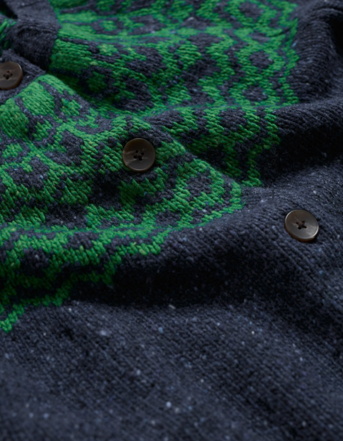 Close-up of a dark blue and green patterned fabric with buttons.