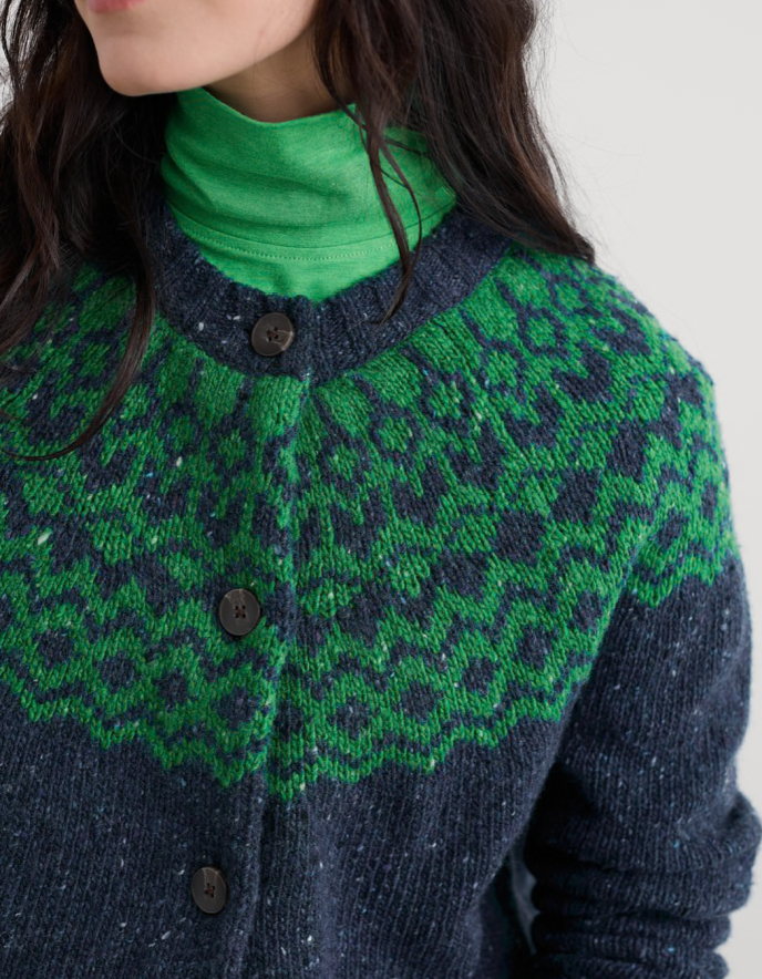 Person wearing a green and navy patterned cardigan with a close-up on the collar and buttons.