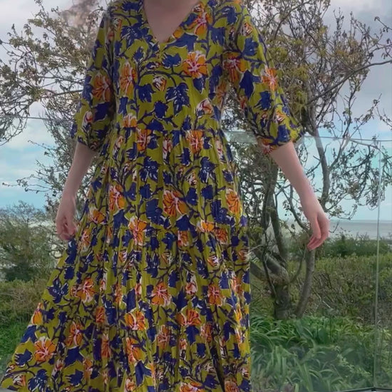 midi cotton floral dress with tiered skirt, elbow length sleeves, v neckline, olive background with indigo and orange florals
