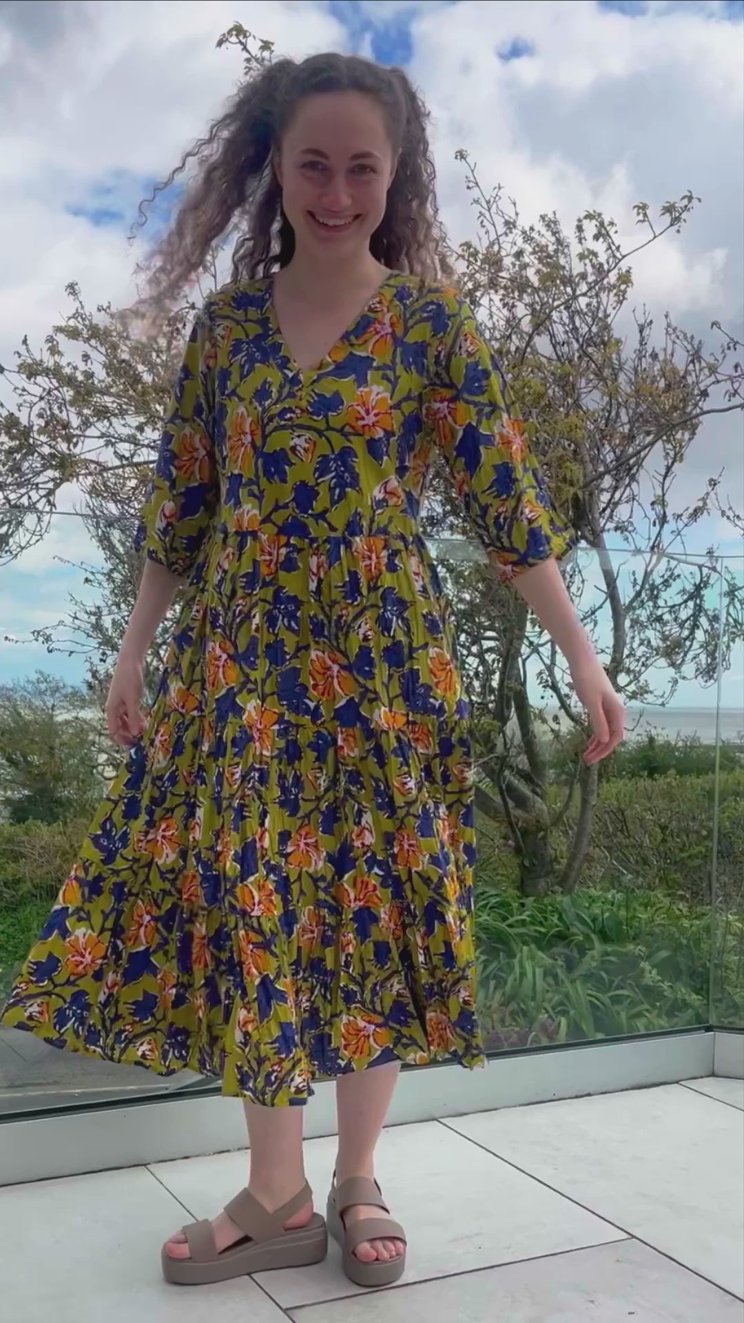 midi cotton floral dress with tiered skirt, elbow length sleeves, v neckline, olive background with indigo and orange florals