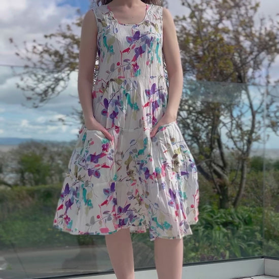 sleeveless cotton summer dress with tired flared shape and front patch pockets, pretty floral print in pinks and purples