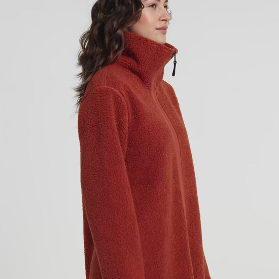 Woman wearing a rust orange sherpa pile fleece  jacket on a white background