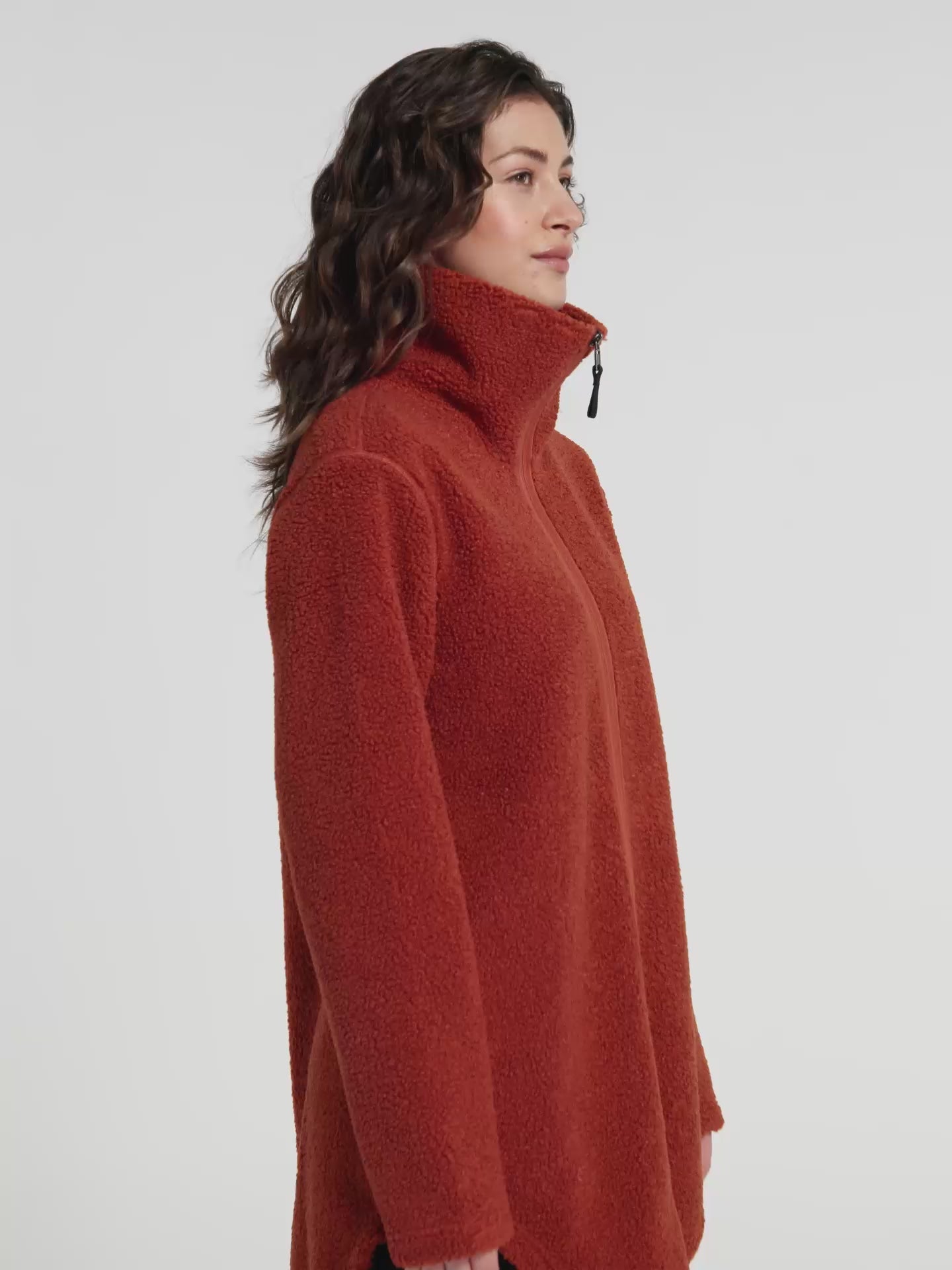 Woman wearing a rust orange sherpa pile fleece  jacket on a white background