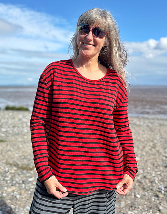 Woman wearing a red and black striped fleecy line long sleeve T shirt on a beach