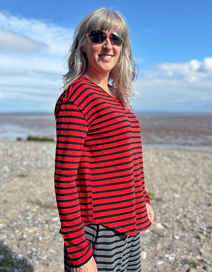 Woman wearing a red and black striped fleecy line long sleeve T shirt on a beach