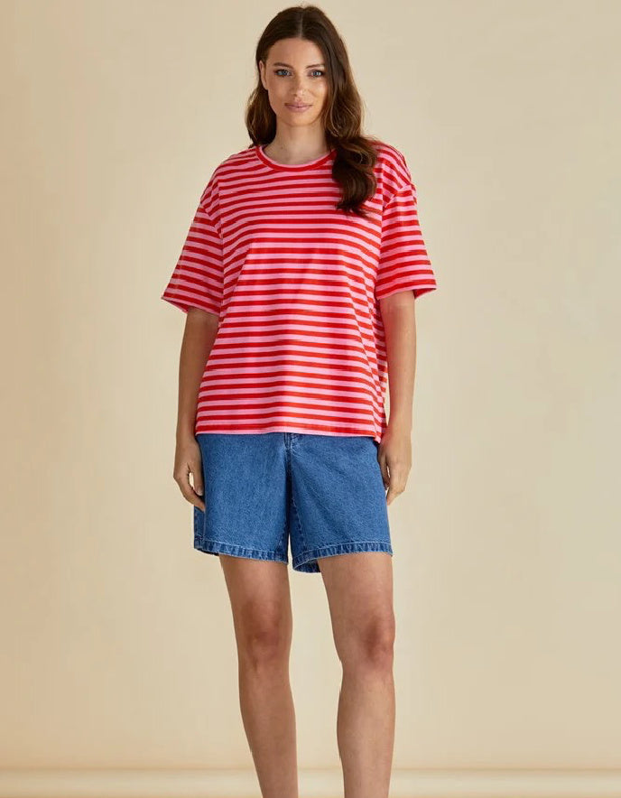 Woman wearing a red and white striped shirt and blue shorts on a beige background