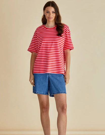Woman wearing a red and white striped shirt and blue shorts on a beige background