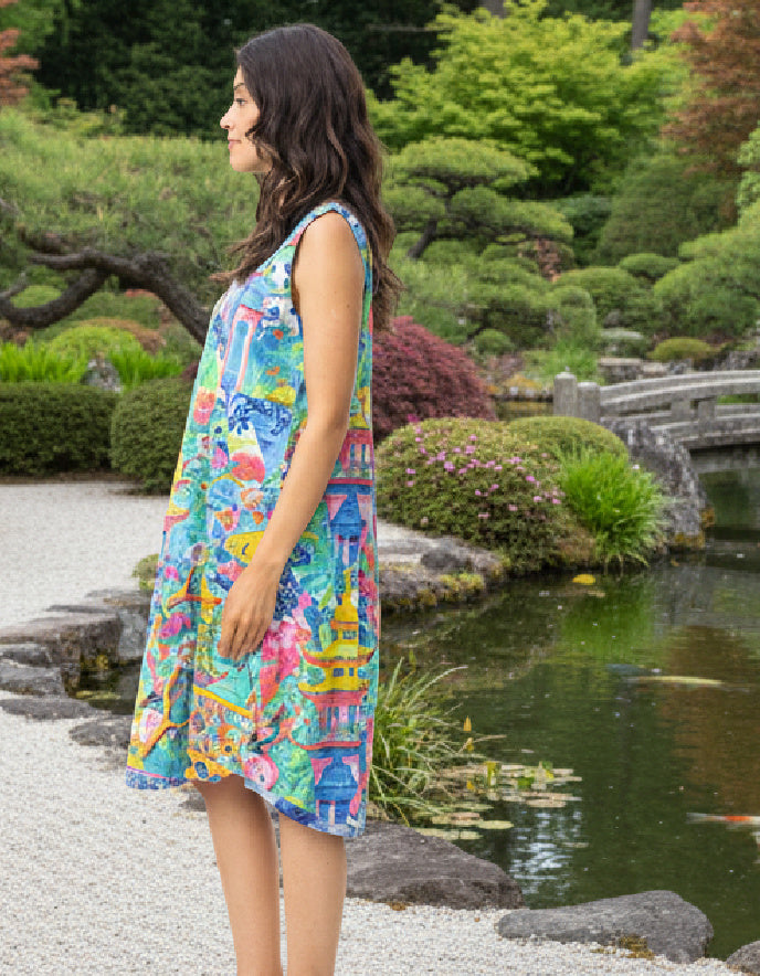 Woman in a colorful dress standing by a pond with greenery in the background