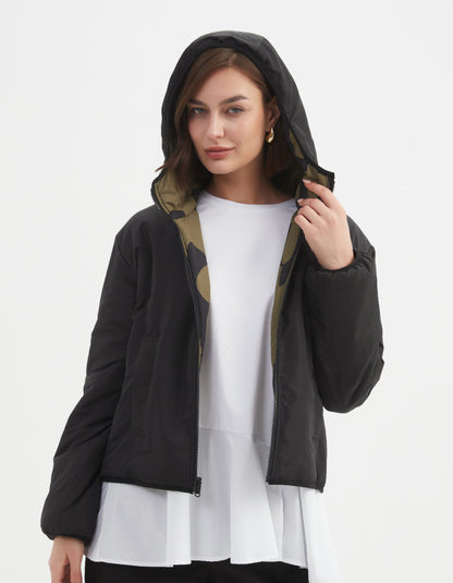 Woman wearing a camouflage olive and black reversible puffer jacket on a white background