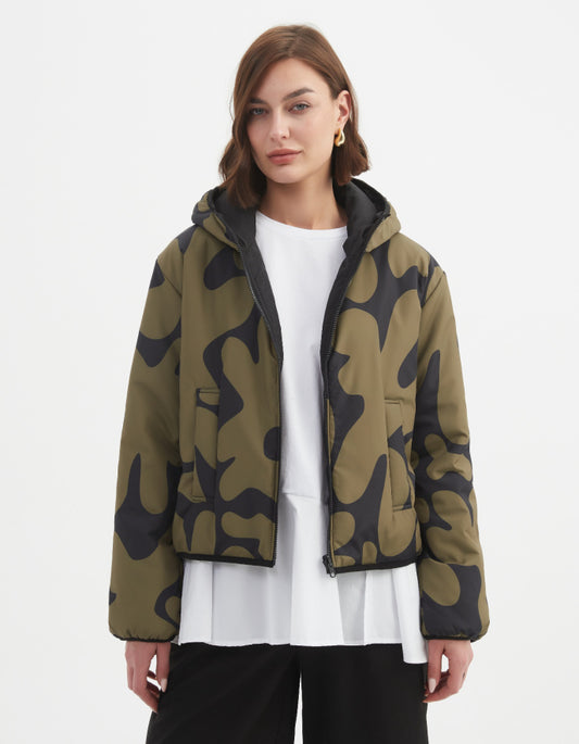 Woman wearing a camouflage olive and black reversible puffer jacket on a white background