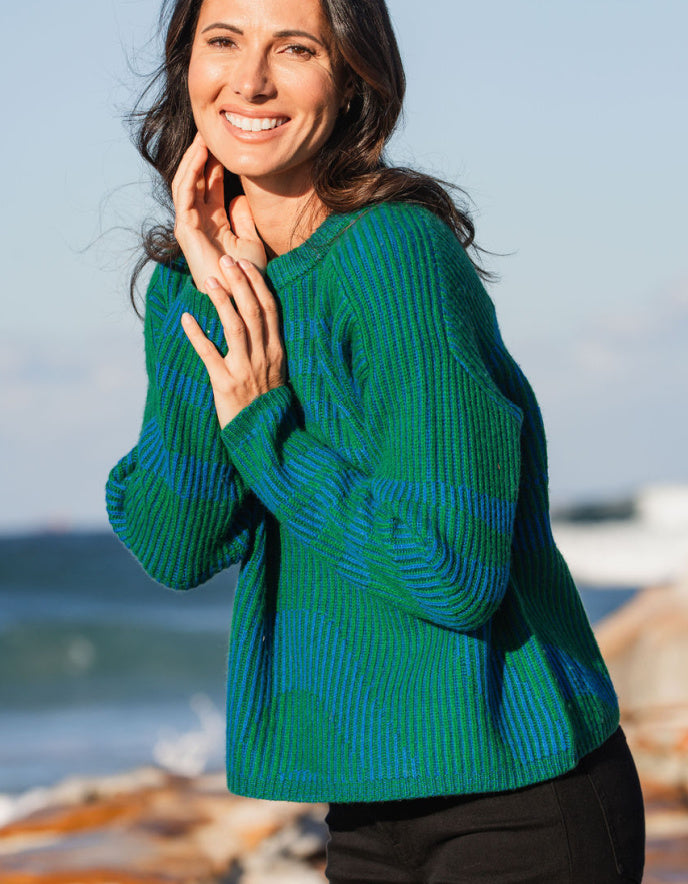Woman wearing a green and blue sweater by the beach