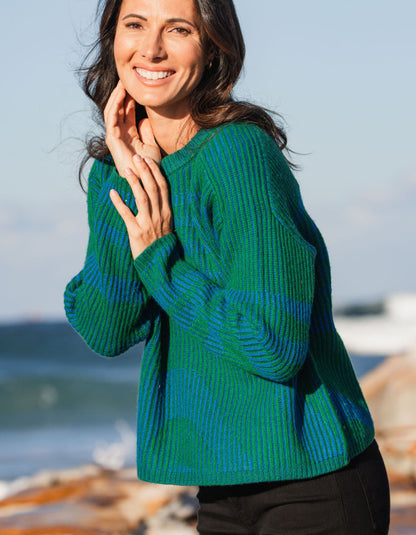 Woman wearing a green and blue sweater by the beach