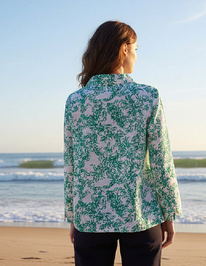 Woman wearing a green and white fish print shirt on a beach