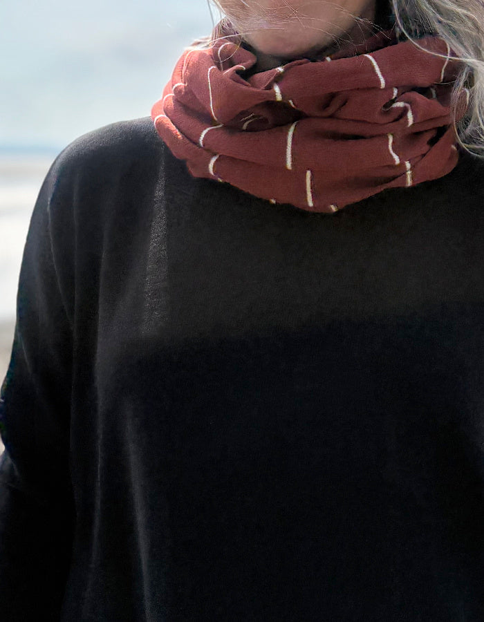 Person wearing a red snood with white stripes against a blurred background