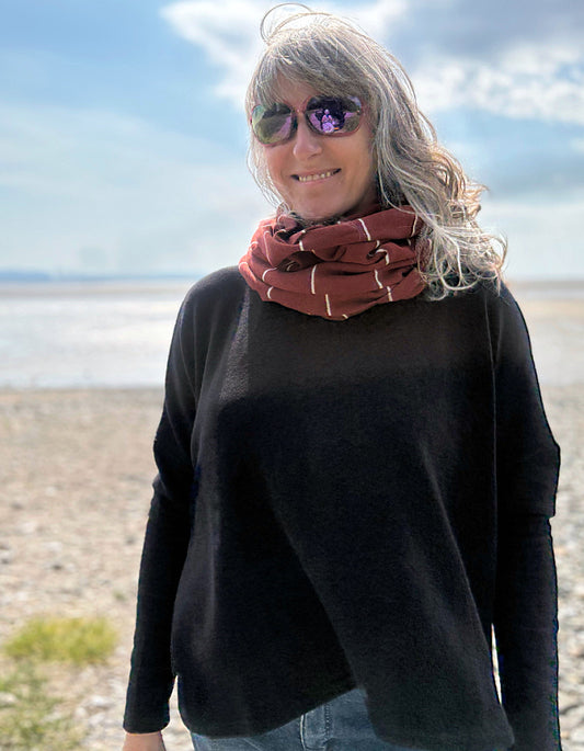 Person wearing a black sweater and red sonood on a beach