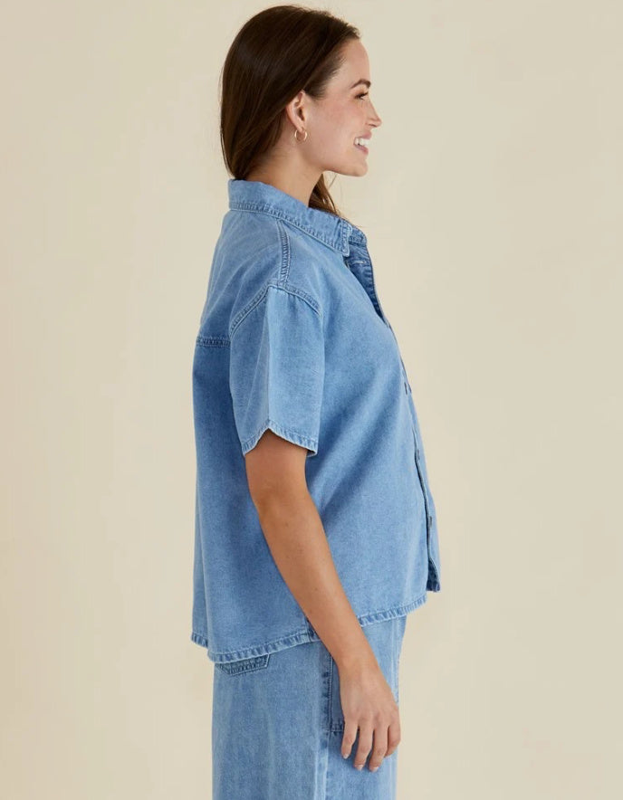 Woman wearing a light blue denim outfit on a beige background