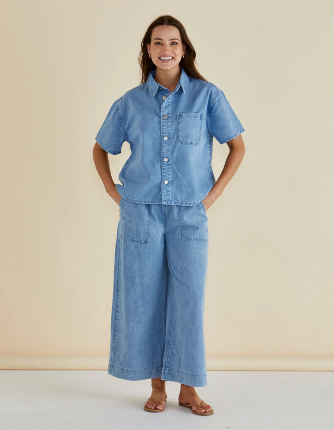 Woman wearing a blue denim outfit against a beige background