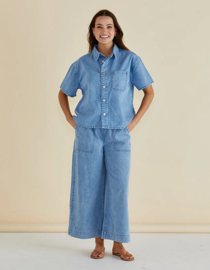 Woman wearing a blue denim outfit against a beige background