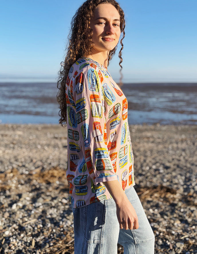 person wearing silk blouse with print of tins of sardines on it