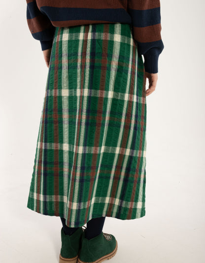 Person wearing a green plaid skirt on a white background