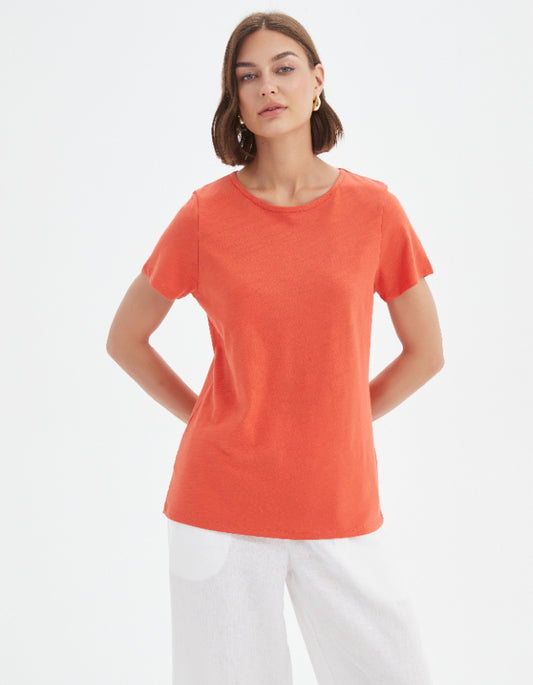 Woman wearing an orange t-shirt and white pants on a white background