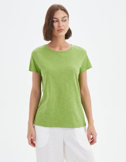 Woman wearing a green t-shirt and white pants on a white background