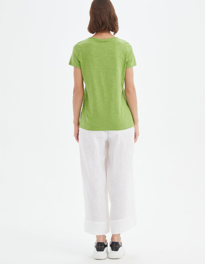 Person wearing a green t-shirt and white pants on a white background