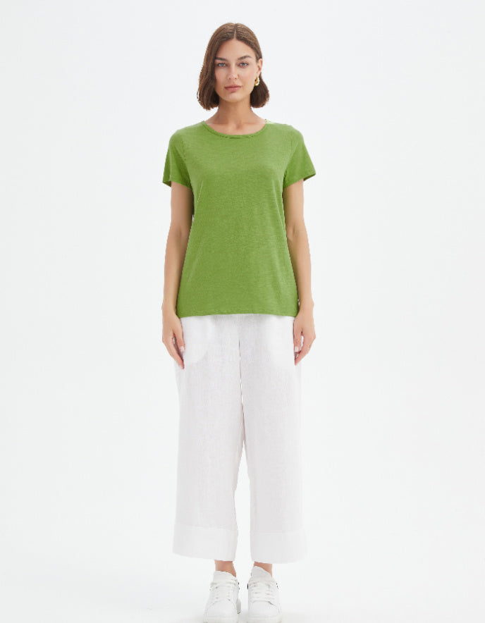 Woman wearing a green t-shirt and white pants on a white background
