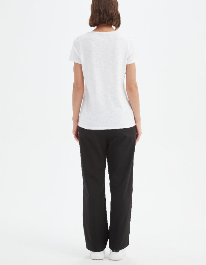 Person wearing a white t-shirt and black pants on a white background