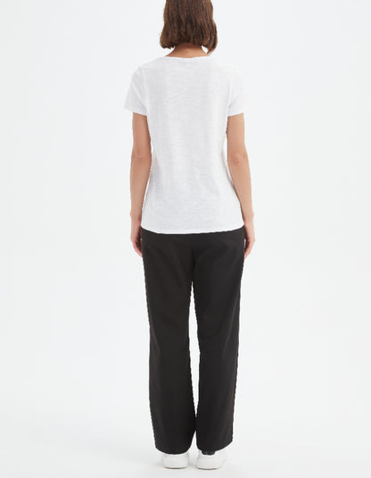 Person wearing a white t-shirt and black pants on a white background