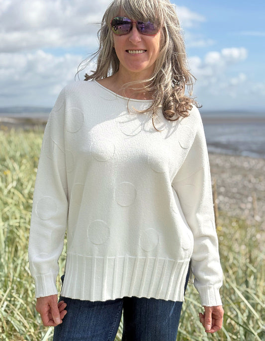Woman wearing a white sweater with a beach and sky background